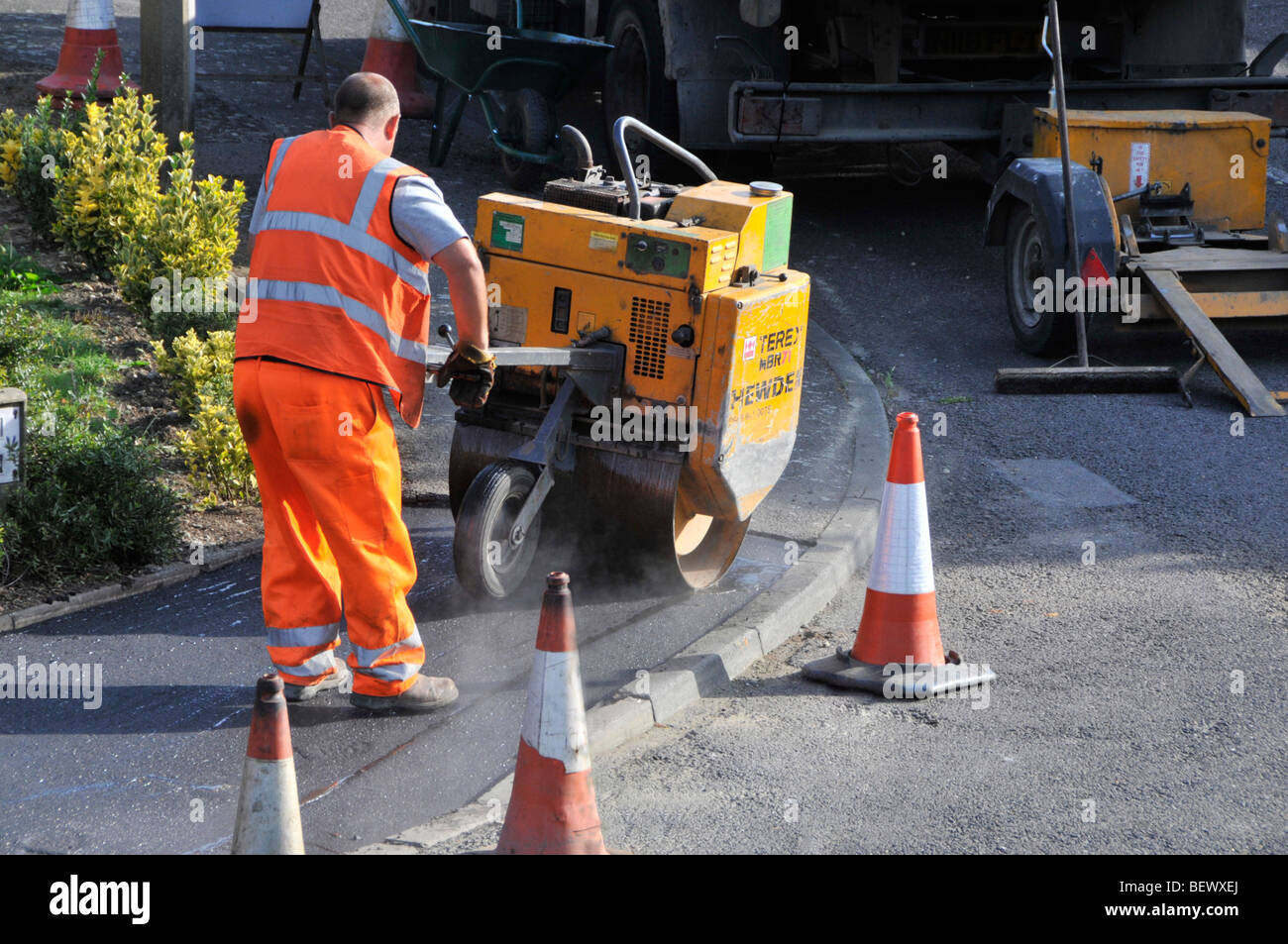 Operai frequentando il marciapiede marciapiede di riparazioni in strada residenziale Foto Stock