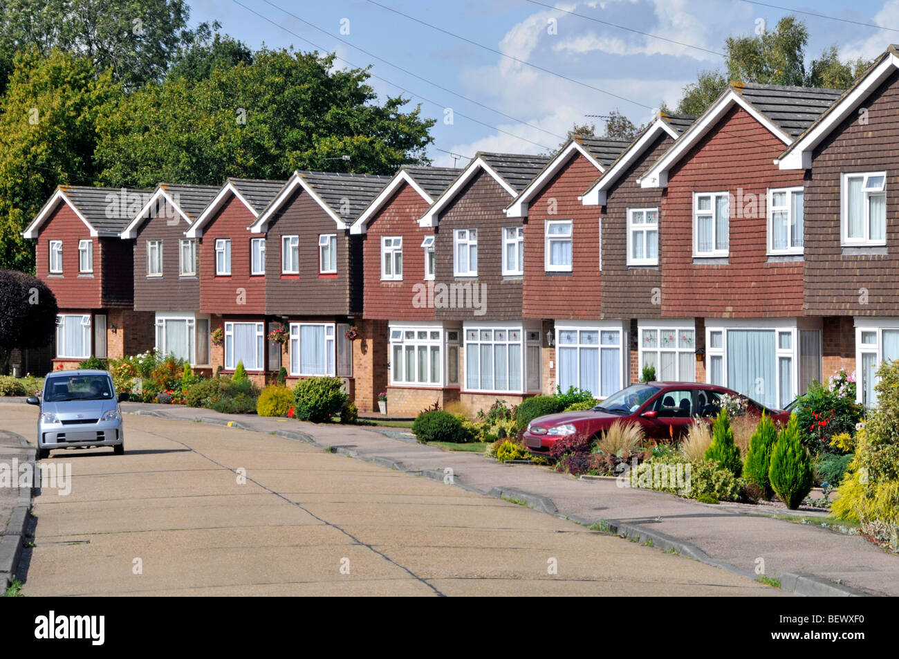 Fila di case in via residenziale di case immobiliari proprietà di sviluppo identico case indipendenti giardini individuali e vialetto auto Inghilterra Regno Unito Foto Stock