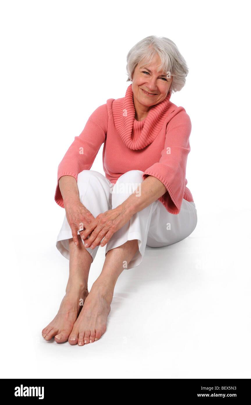 Attraente senior donna sorridente seduto su uno sfondo bianco Foto Stock