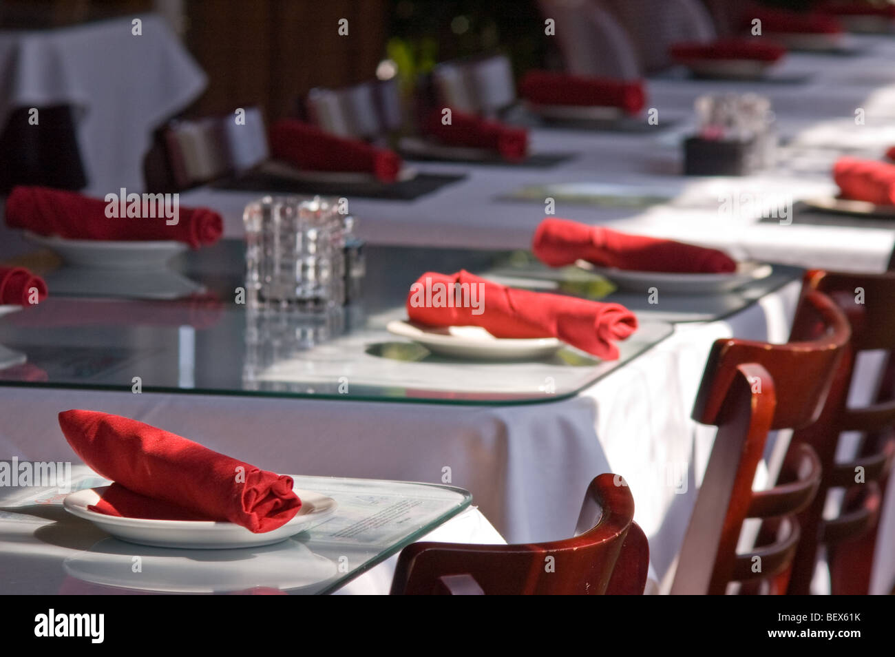 Le tabelle in un ristorante allestito con tovaglia bianca e tovaglioli rosso Foto Stock