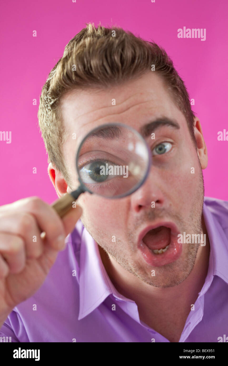 Giovane uomo cerca attraverso la lente di ingrandimento Foto Stock