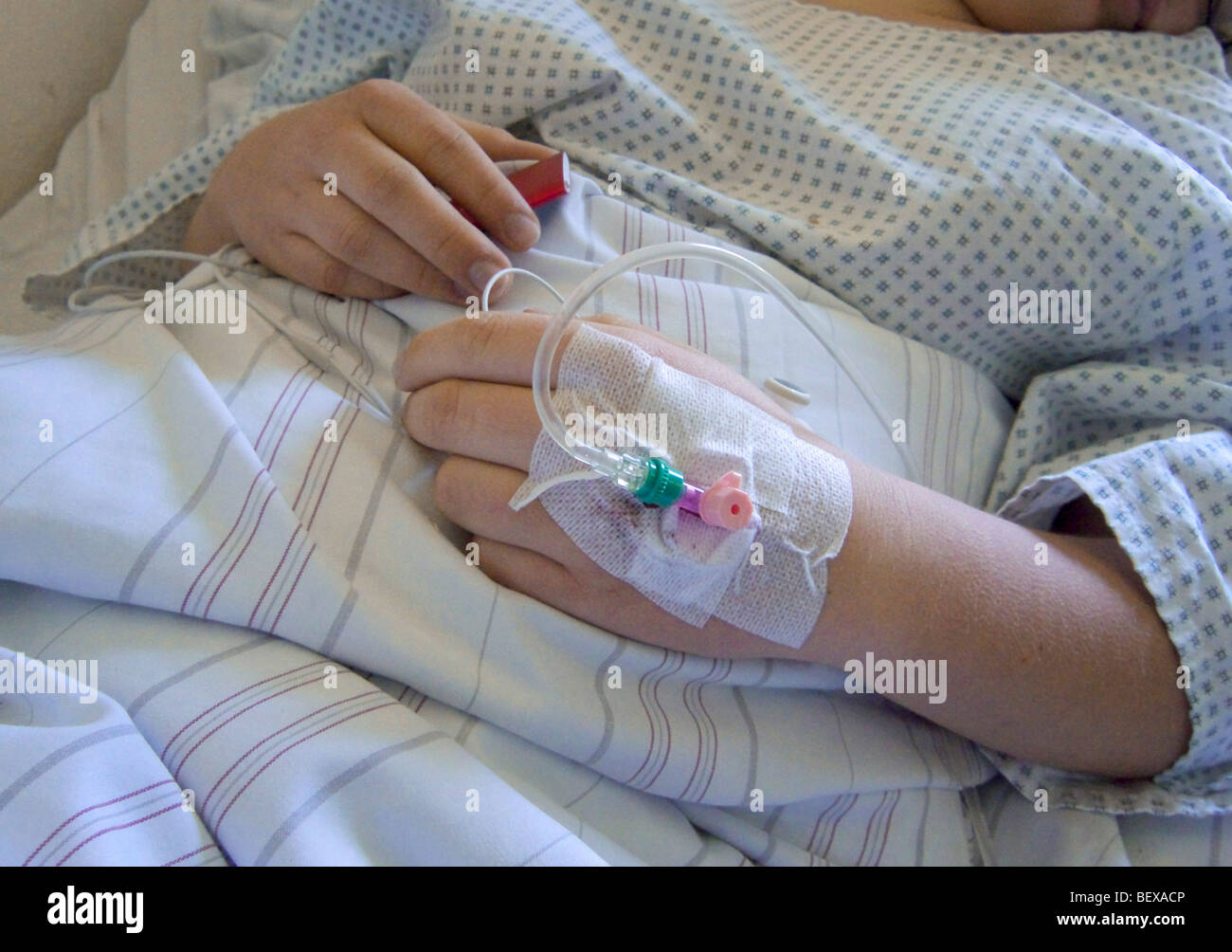 Paziente con gocciolamento endovenoso attaccato sulla mano. Foto Stock