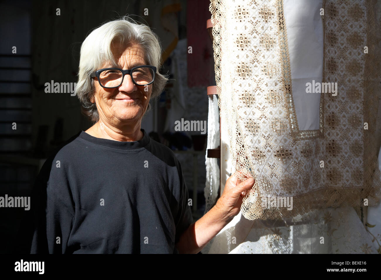 Il vecchio pelo grigio vedova in piedi con i tradizionali pizzi fatti a mano al di fuori del negozio di famiglia in pano lefkara repubblica di Cipro in Europa Foto Stock