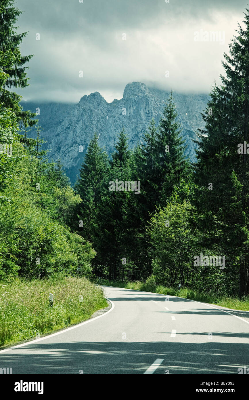 Viaggiando lungo una strada aperta attraverso un bosco in montagna in Baviera, Germania, Europa Foto Stock