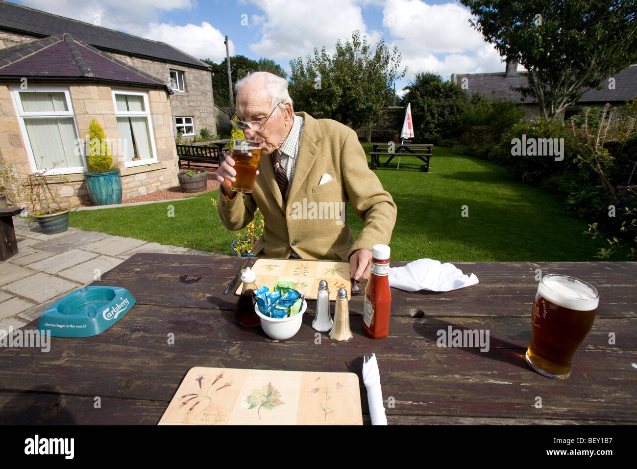 Il vecchio uomo in un giardino della birra bere una pinta di birra inglese Foto Stock