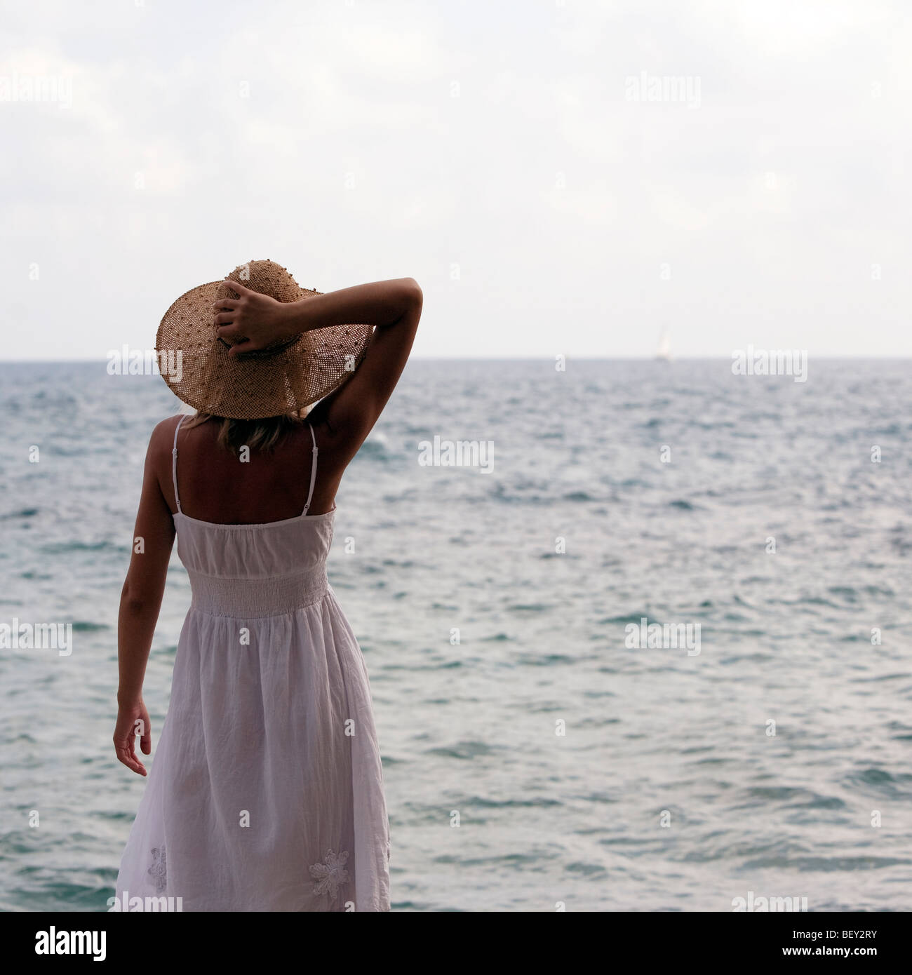 Giovane donna con cappello di paglia in piedi di fronte al mare Foto stock  - Alamy