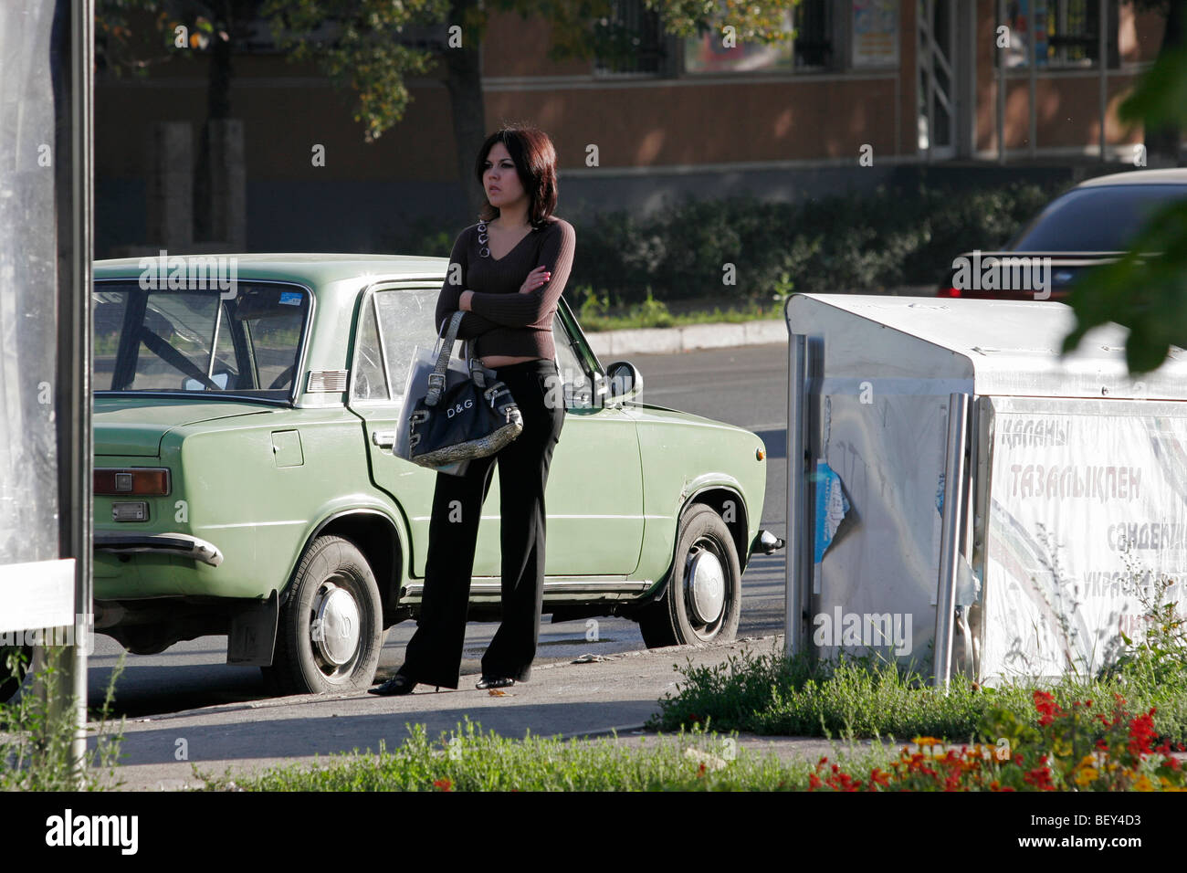 Ragazza kazaka è in attesa di un bus sulla strada ad Almaty in Kazakistan. Foto Stock