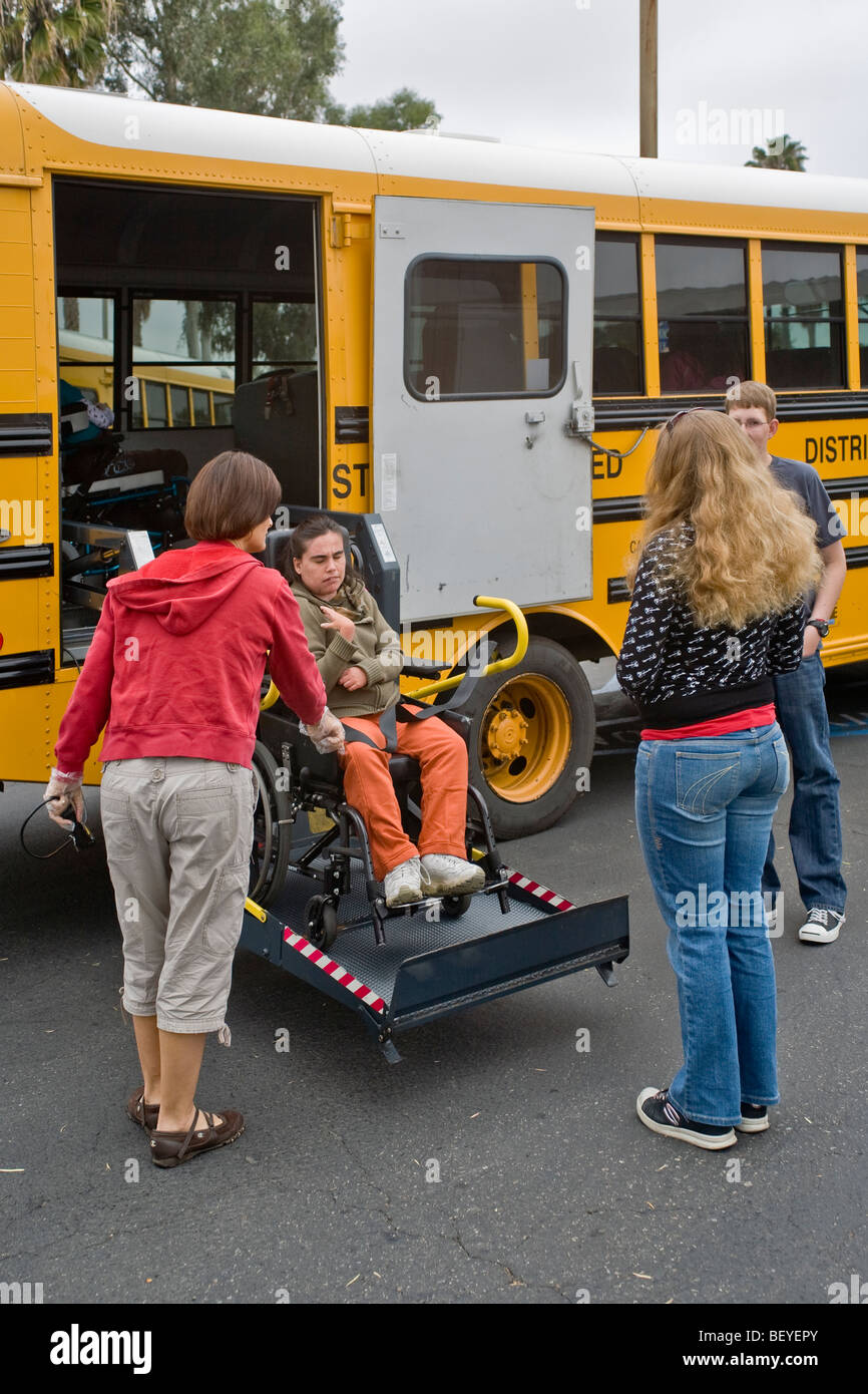 Una sedia a rotelle a particolari esigenze studente arriva alla scuola tramite un 'portatori di handicap Ascensore su di una variante di bus di scuola.California Foto Stock