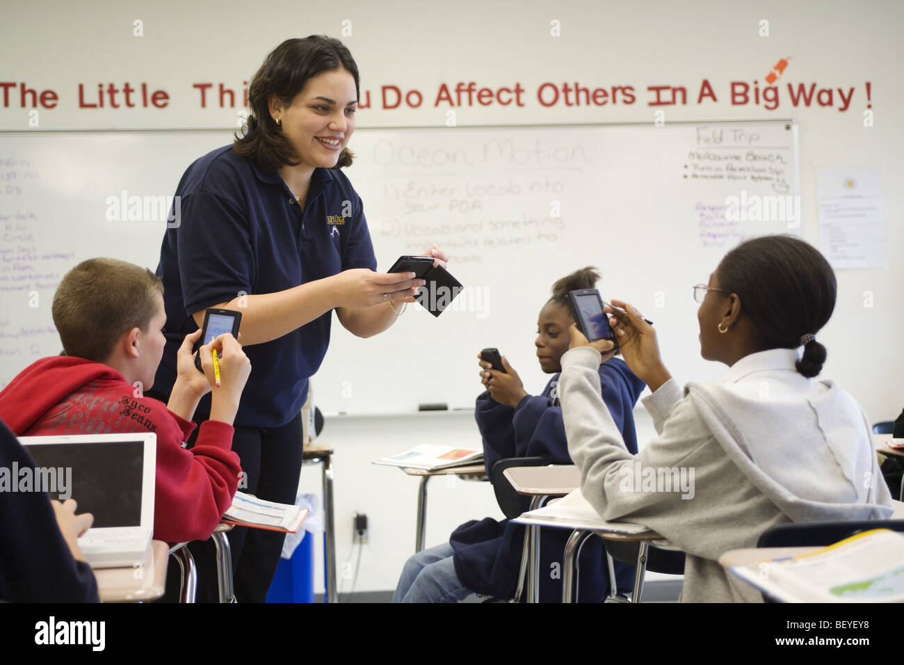 Multi etnico gruppo di studenti in aula con Palm del computer e insegnante femmina, Foto Stock