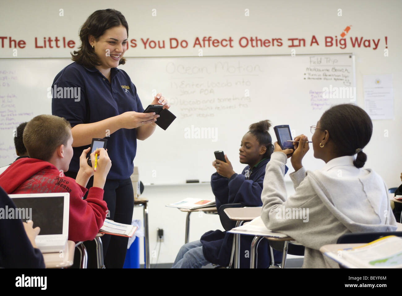 Multi etnico gruppo di studenti in aula con Palm del computer e insegnante femmina, Foto Stock