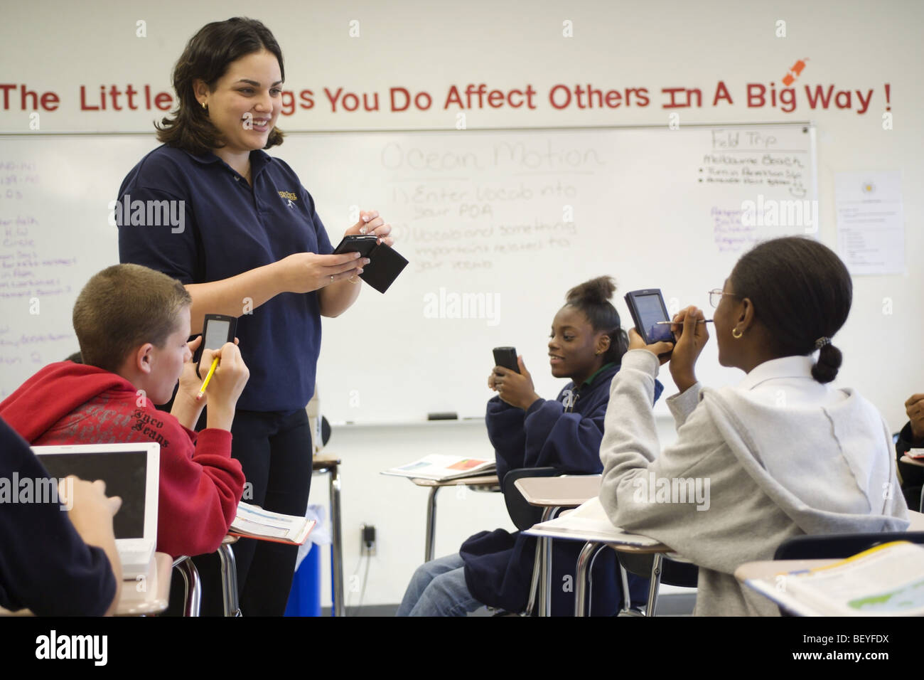 Multi etnico gruppo di studenti in aula con Palm del computer e insegnante femmina, Foto Stock