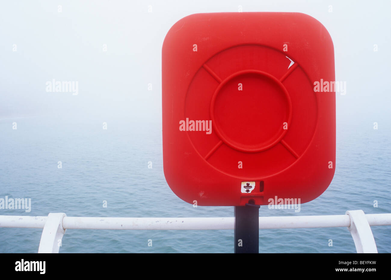 Dettaglio della red attrezzature di salvataggio sul palo da ringhiere in bianco con mare calmo nella nebbia al di là Foto Stock