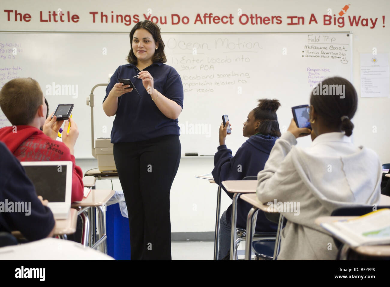 Multi etnico gruppo di studenti in aula con Palm del computer e insegnante femmina, Foto Stock
