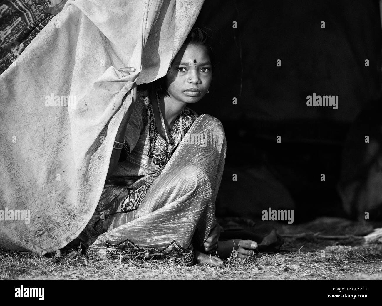 Povero indiano ragazza seduta fuori dalla sua tenda a casa. Monocromatico Foto Stock
