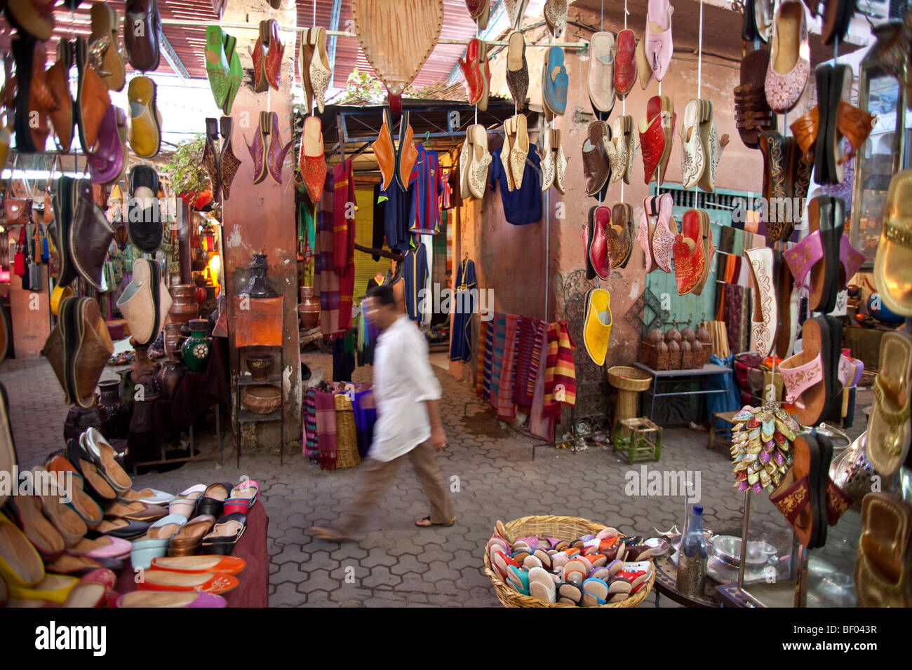 Un uomo cammina passato negozio di calzature nel souk di Marrakech, Marocco Foto Stock