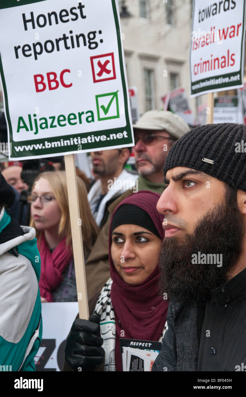 Marzo per Gaza & contro BBC Pro-Israel Bias. Musulmani l uomo e la donna nella folla con targhetta confrontando la BBC e Al Jazeera Foto Stock