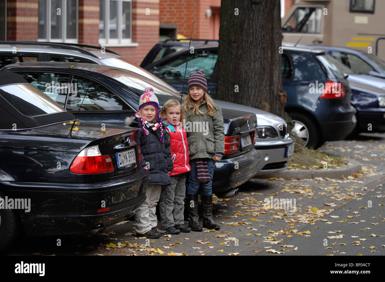 Le ragazze giovani attraversare una strada tra le vetture in autunno Foto Stock