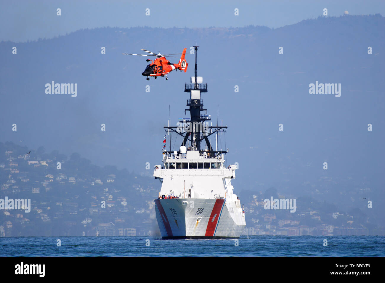 Guardacoste Bertholf WMSL (750) è scortato attraverso la baia di San Francisco da un HH-65C Delfino elicottero. Foto Stock