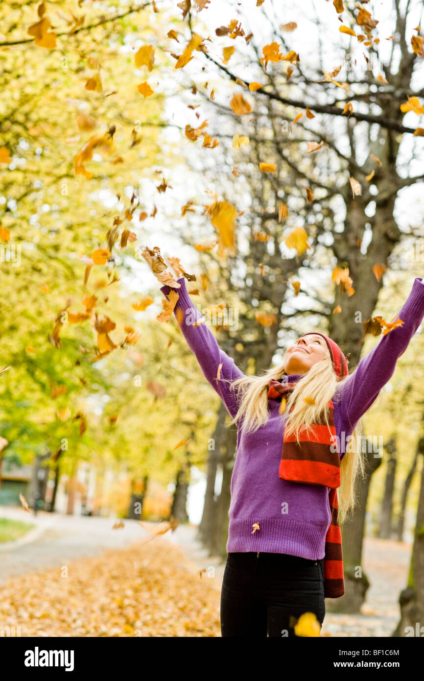Una donna che gioca con foglie di autunno, Stoccolma, Svezia. Foto Stock