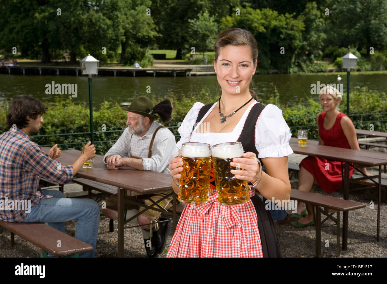 Tradizionalmente un vestito donna tedesca che serve birra in un giardino della birra Foto Stock