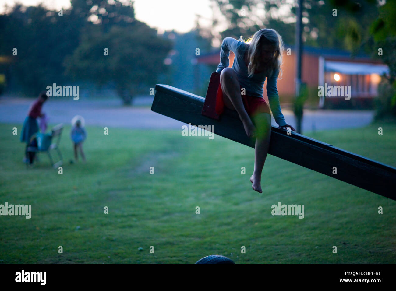 La madre e le figlie su un parco giochi al crepuscolo, Svezia. Foto Stock