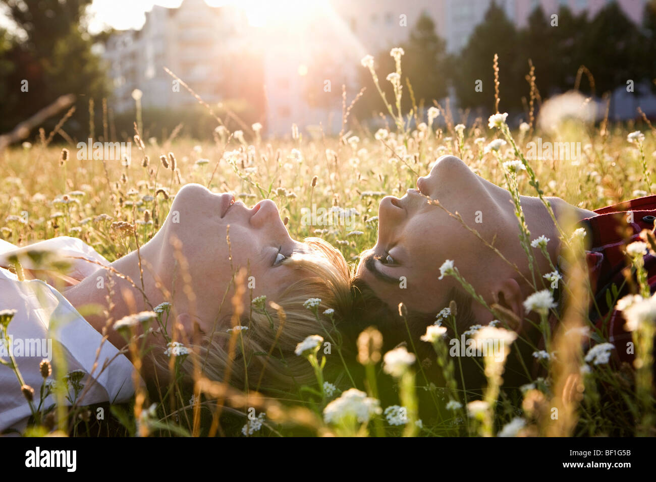 Una giovane coppia giacendo in sulle loro spalle in erba, close-up Foto Stock