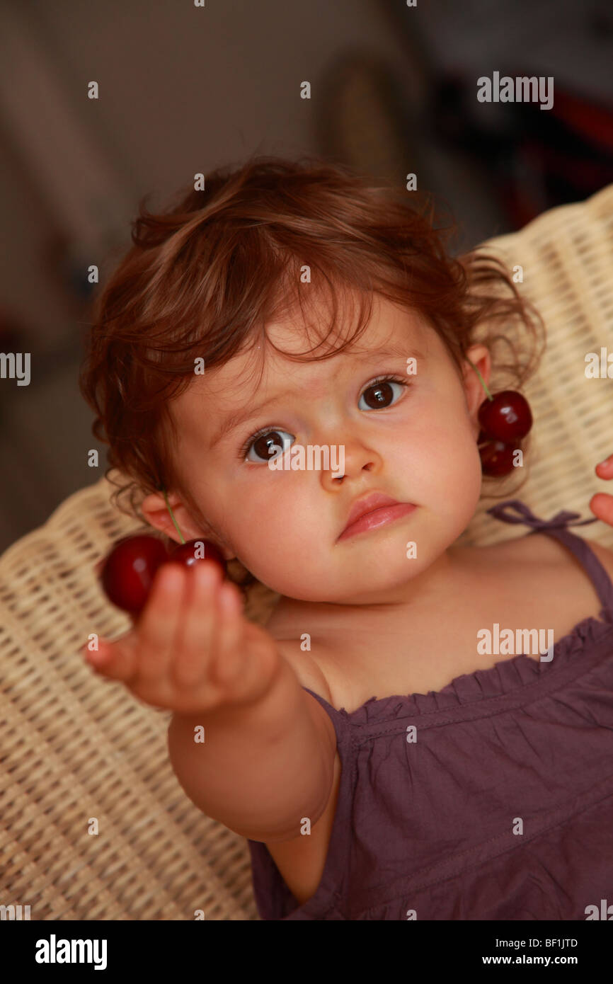 Diciotto mesi Baby girl Mangiare le ciliegie Foto Stock