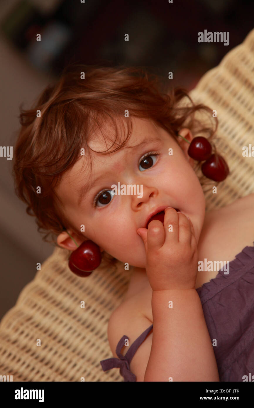 Diciotto mesi Baby girl Mangiare le ciliegie Foto Stock