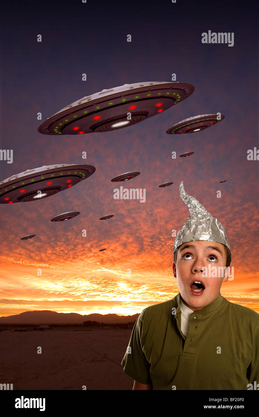 Un ragazzo che indossa un stagno-foil hat osserva uno squadrone di UFO. Foto Stock