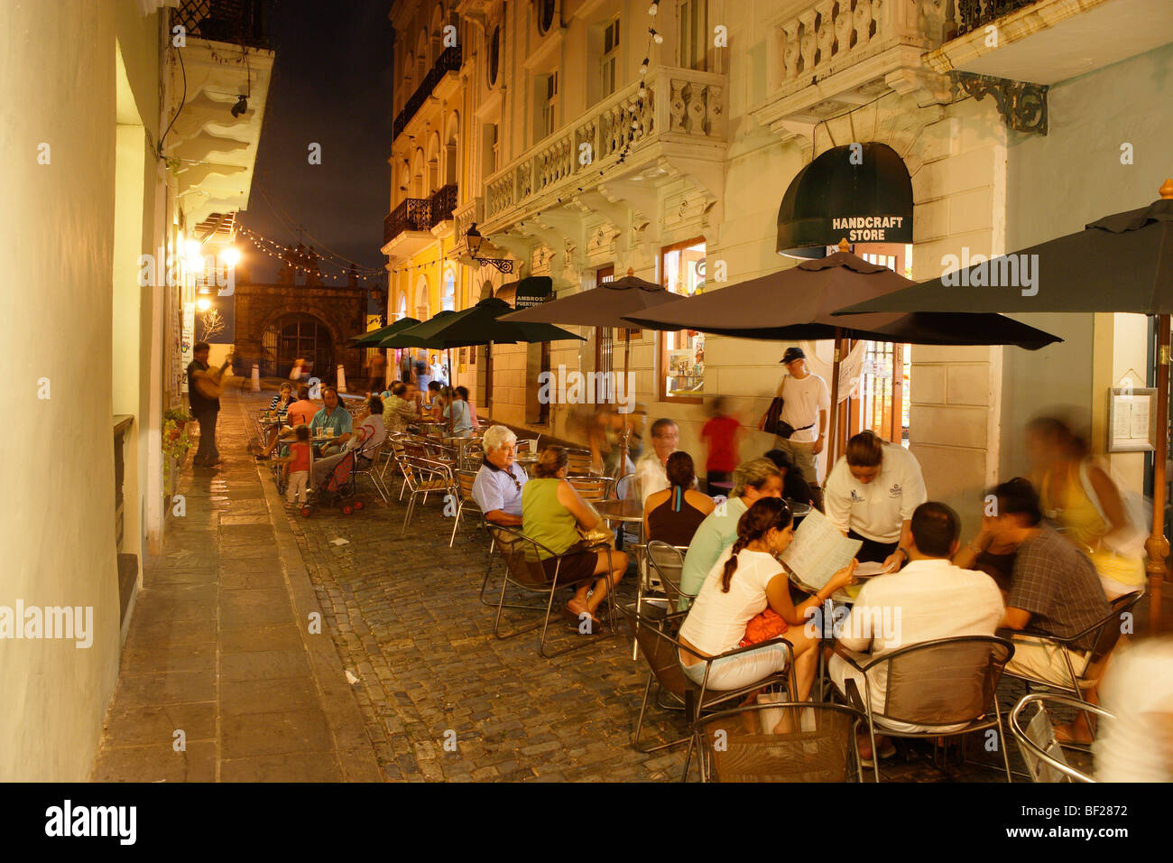 La gente seduta davanti a un caffè presso il centro storico di sera, Calle de Christo, San Juan, Puerto Rico, Caraibi, America Foto Stock