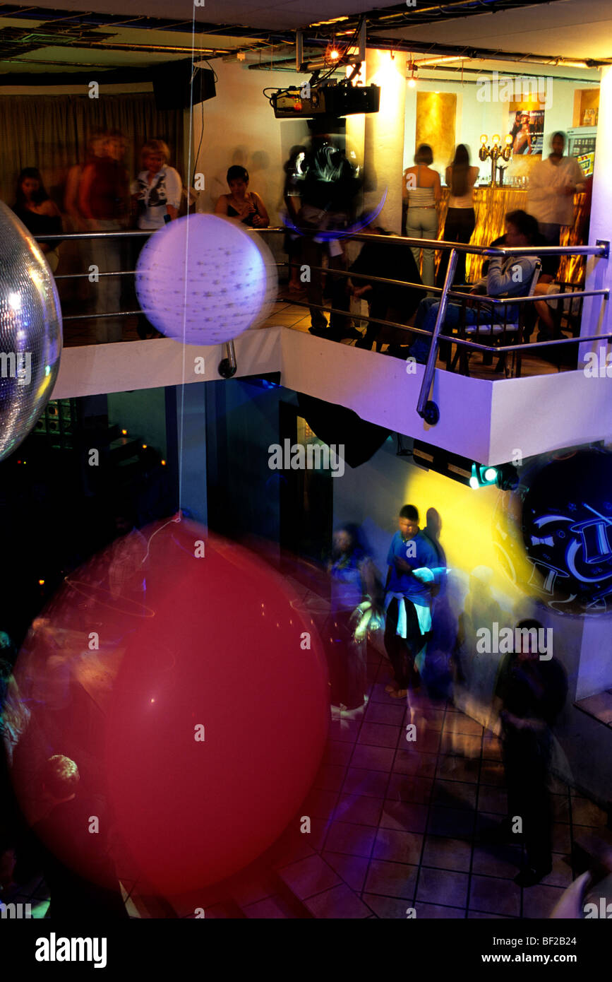 Interno di una discoteca con palloncini, discoteca globe e spotlight, con i festaioli bevendo e chiacchierando Foto Stock