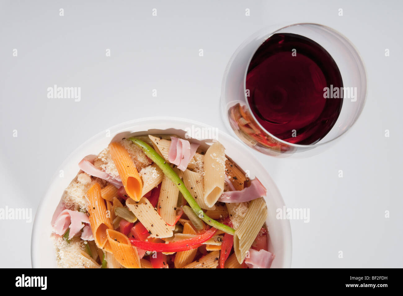 Angolo di alta vista di una ciotola di penne di pasta con un bicchiere di vino Foto Stock