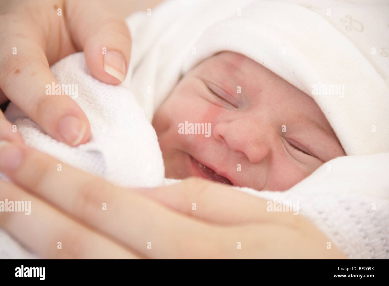 Ritratto di un neonato ragazza avvolto in una coperta, addormentato veloce essendo tenuto da sua madre la mano, poche ore dopo la nascita. Foto Stock