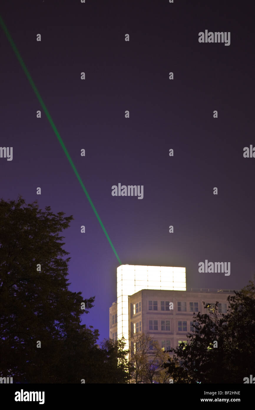 Skyline di Berlino di notte con un unico luminoso edificio e fascio Laser Foto Stock