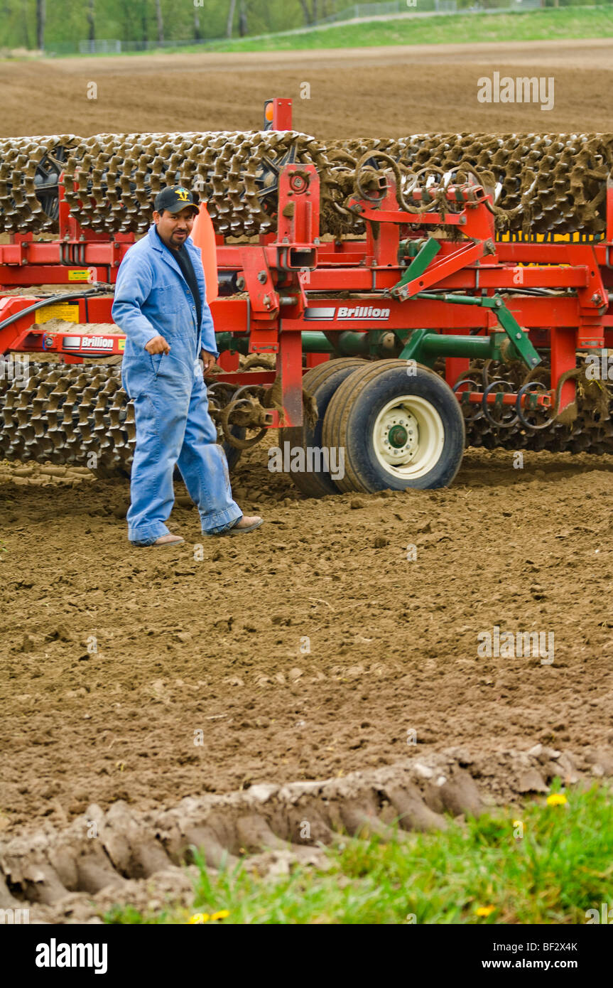 Un lavoratore di campo controlla una trinciatrice per accertarsi che esso sia adeguatamente preparato per essere spostati in un altro campo / Burlington, Washington, Stati Uniti d'America. Foto Stock