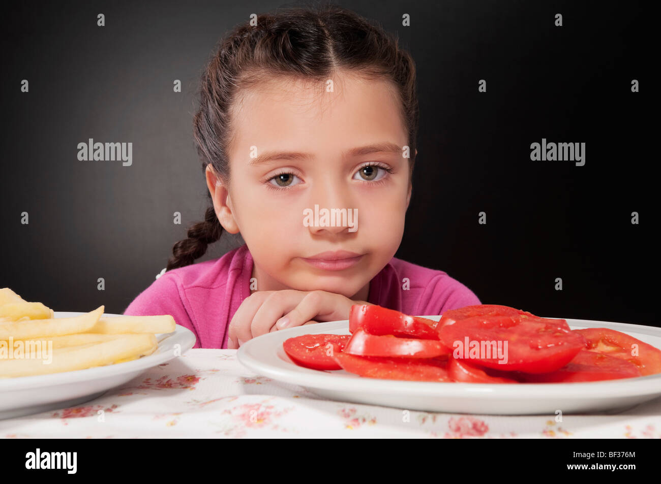 Close-up di una ragazza accigliata con un piatto di fette di pomodoro Foto Stock