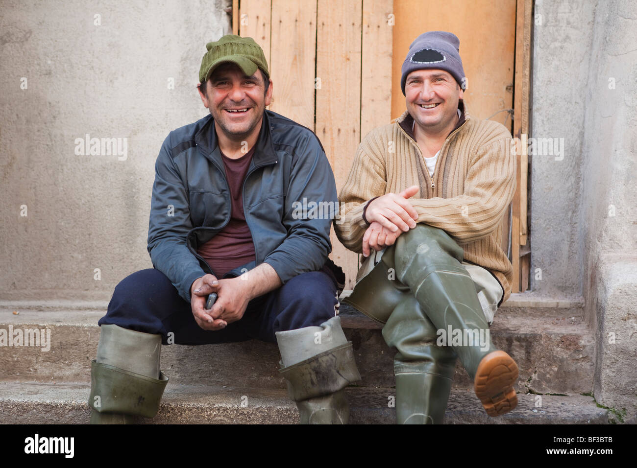 Due pescatore seduto sui gradini, ridendo Foto Stock