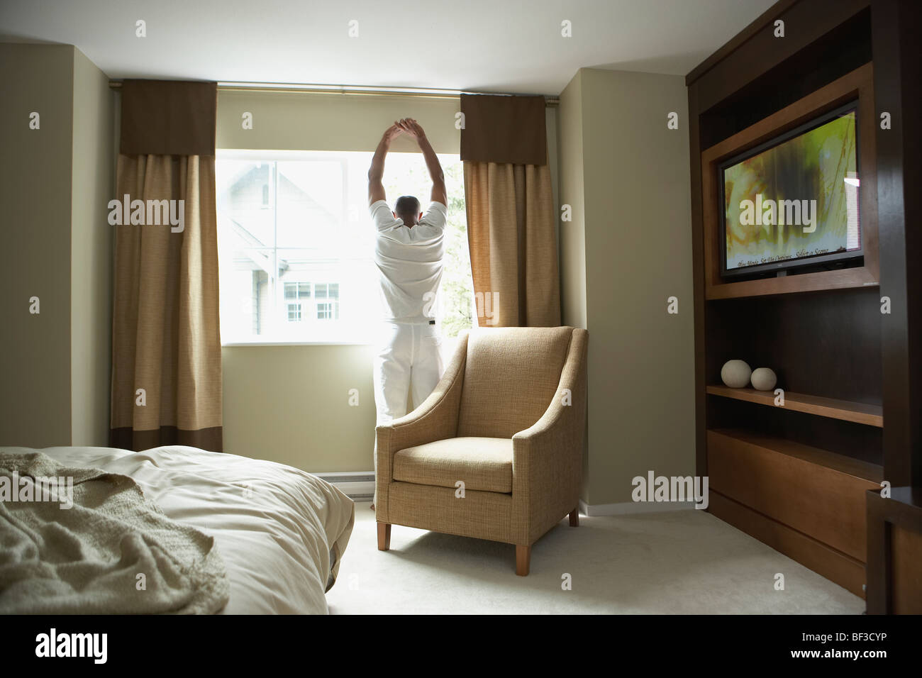 Uomo di stretching e guardare fuori dalla finestra Foto Stock