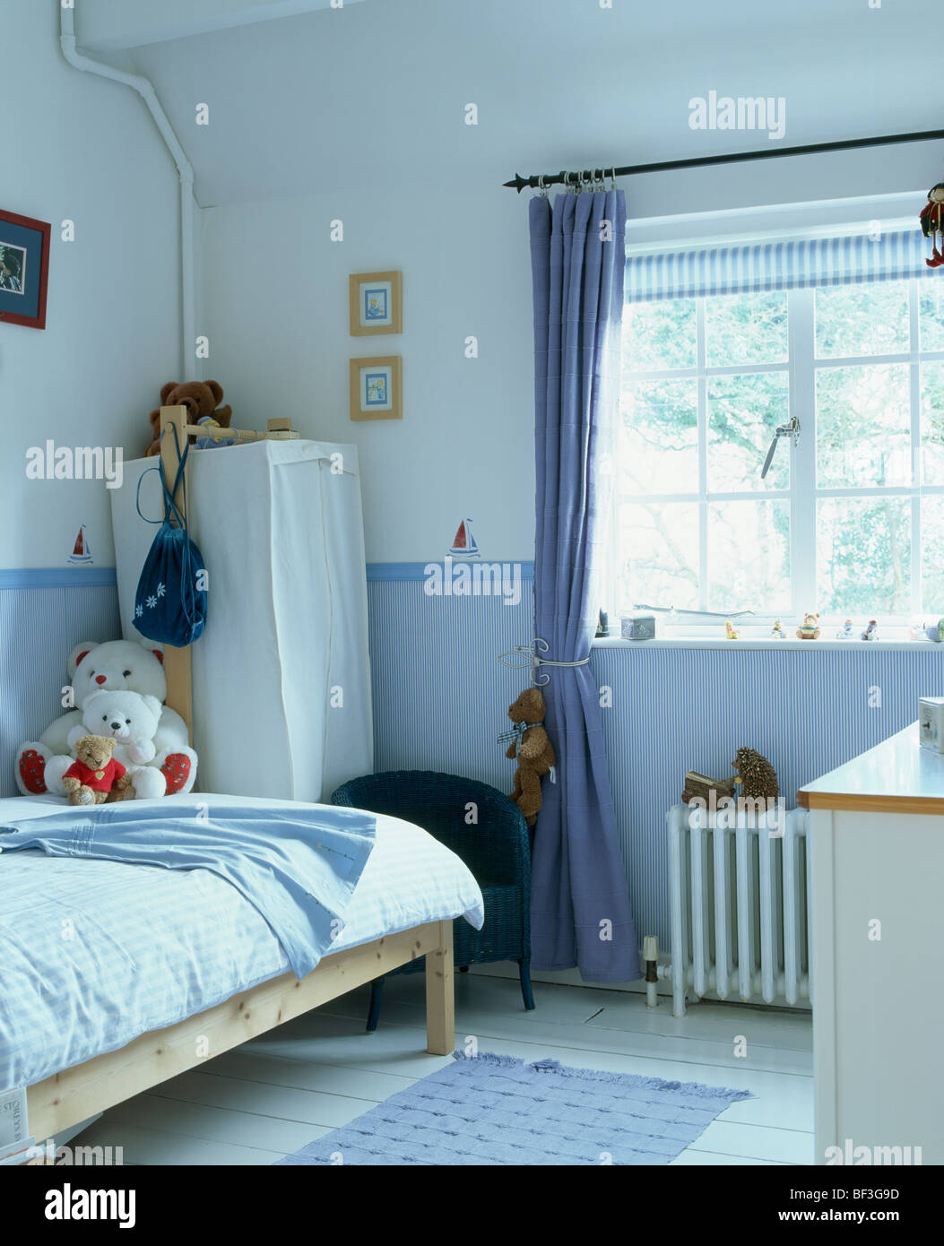 La tendina blu in corrispondenza della finestra in camera bambino con sfondo blu dado e tenda-armadio in un angolo della stanza Foto Stock