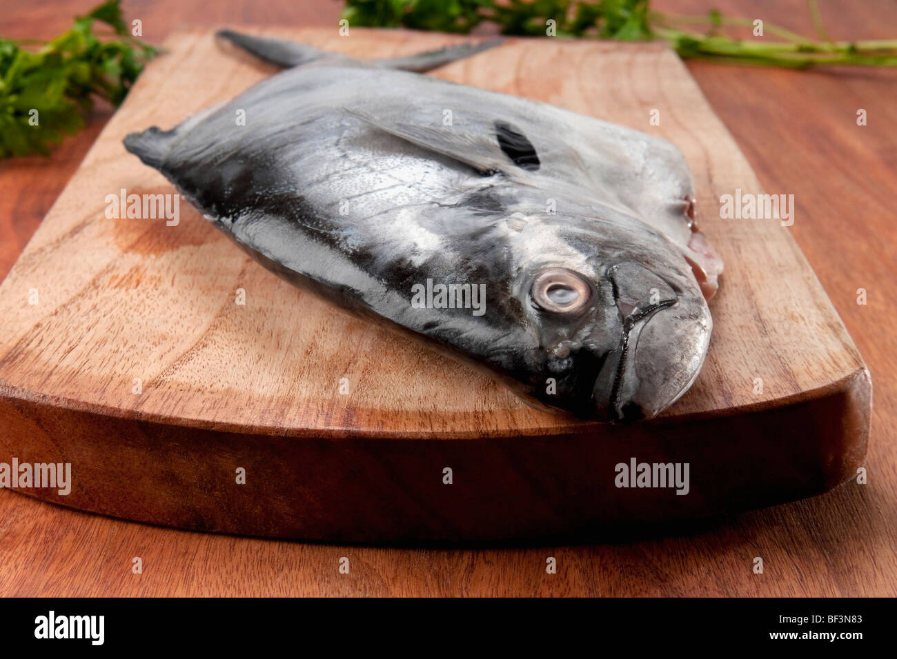 Close-up di un intero pesce crudo su un tagliere Foto Stock