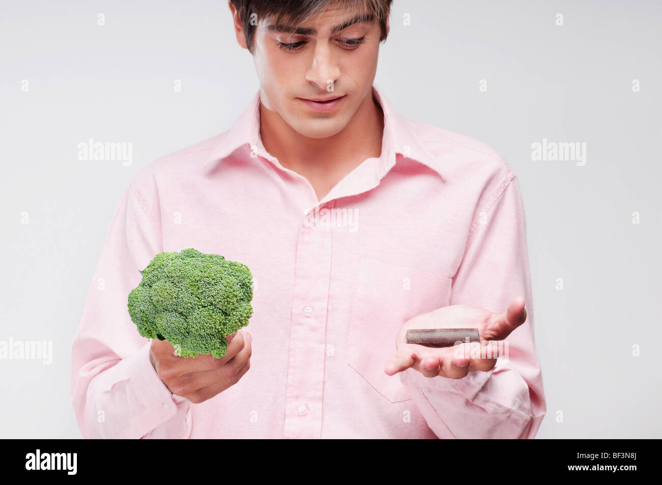L'uomo scegliendo tra i broccoli e cioccolata Foto Stock