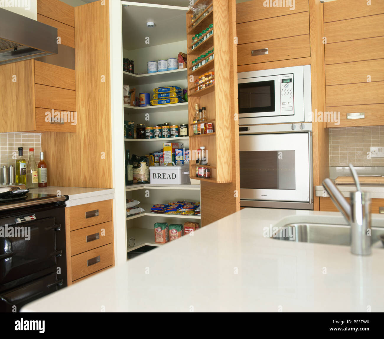 Unità di isola con sotto-set lavello in corian bianco piano di lavoro nella  piccola cucina con dispensa aperta armadio Foto stock - Alamy