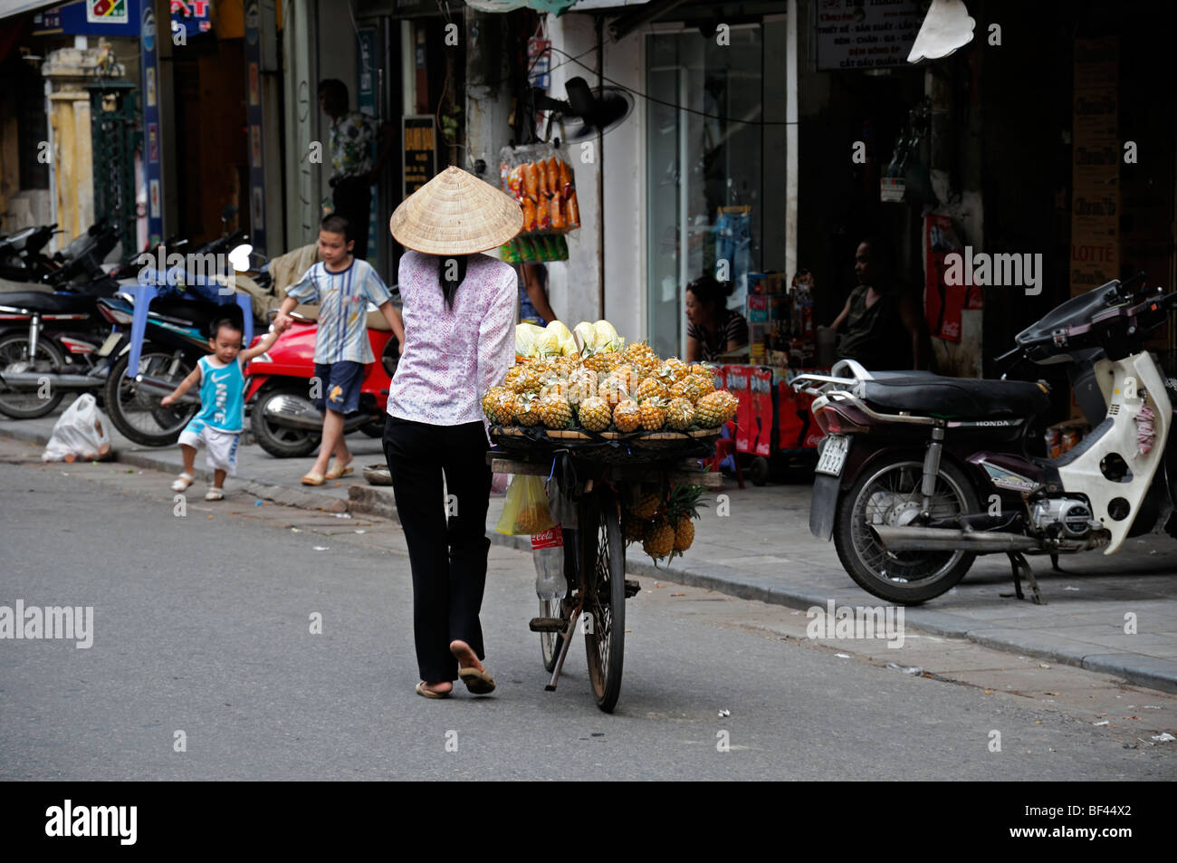 Donna che trasportano il trasporto di effettuare il trasporto di carico pesante sovraccarico di frutta noleggio di Ho chi minh in Vietnam Foto Stock