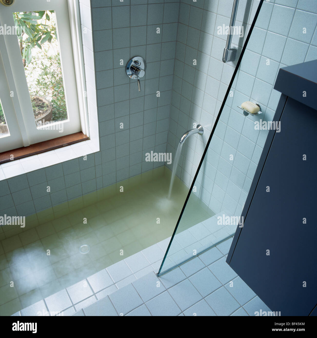 Versare acqua dal rubinetto cromato in vasca con box doccia in vetro ... Doccia in vasca