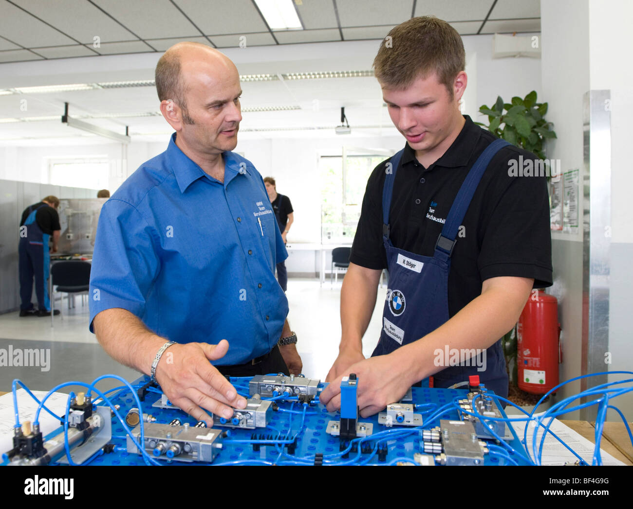 Master, Andreas Fischer, spiegando un circuito elettrico ad un apprendista in BMW training center for automotive meccatronica Foto Stock