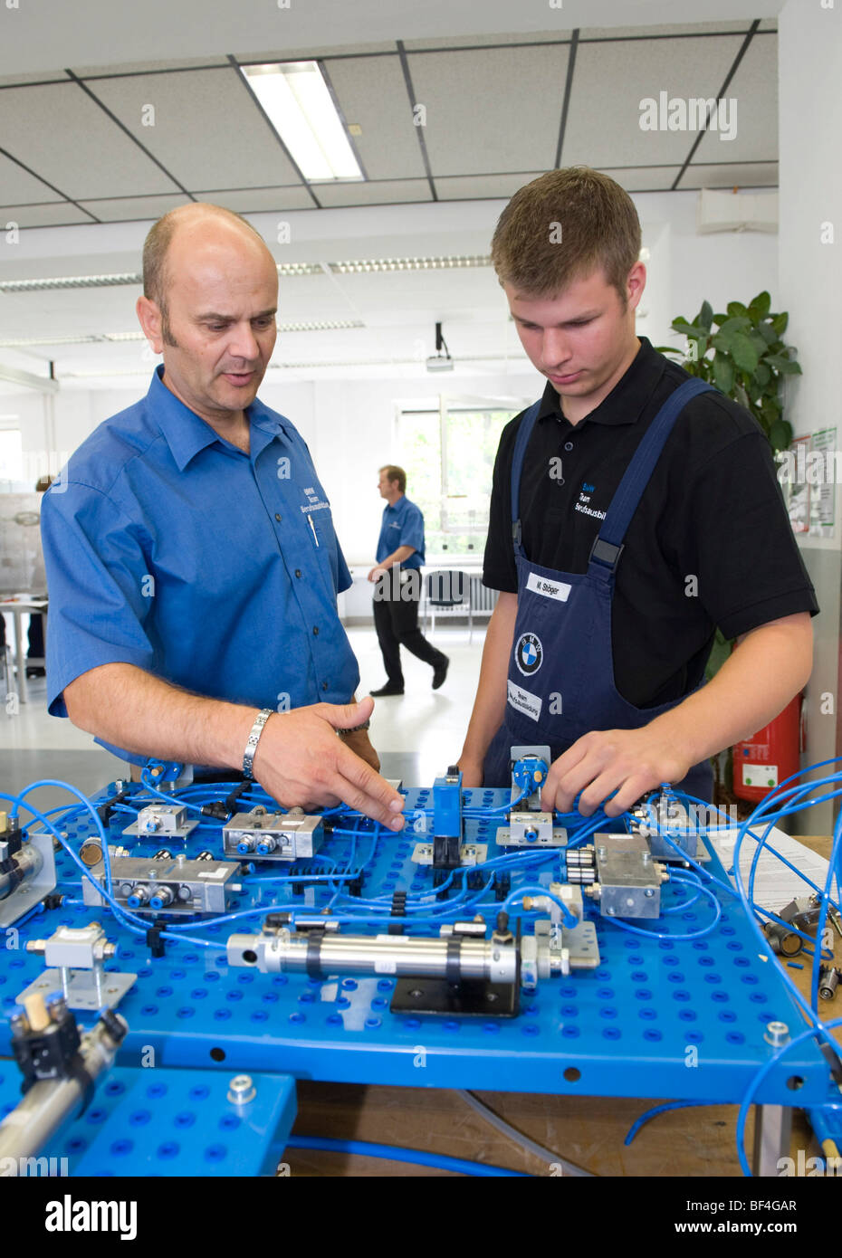 Master, Andreas Fischer, spiegando un circuito elettrico ad un apprendista in BMW training center for automotive meccatronica Foto Stock