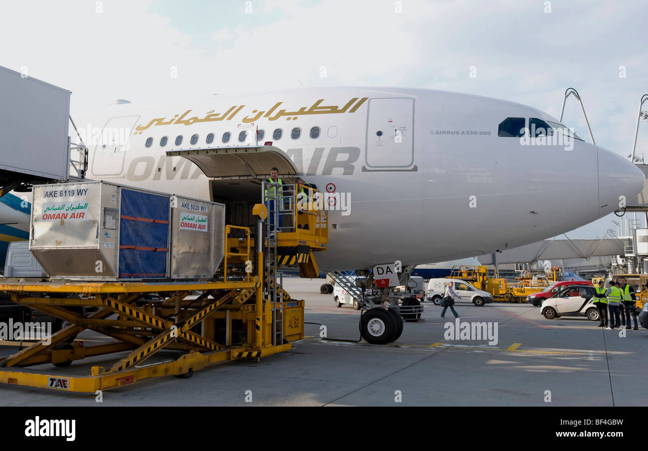Personale di terra lo scarico di un Airbus A330-200 della compagnia aerea Oman Air, Aeroporto di Monaco di Baviera, Germania, Europa Foto Stock