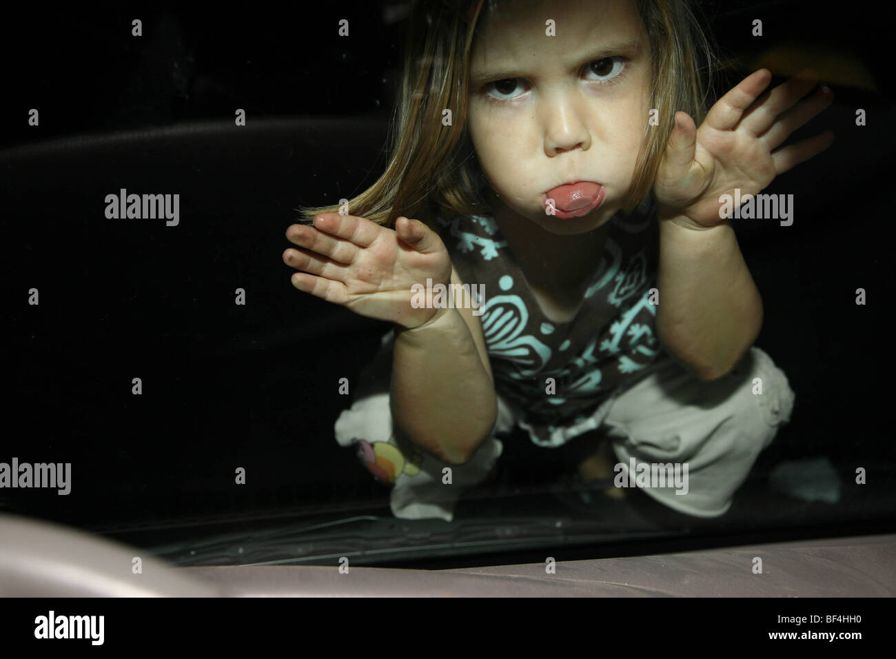 Ragazza il suo incollaggio con la lingua fuori cercando arrabbiato. Quattro-anno-vecchia ragazza sempre arrabbiato a sua madre. Foto Stock