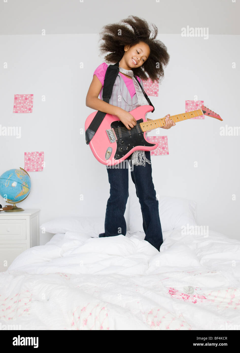 Ragazza africana a suonare la chitarra sul letto Foto Stock