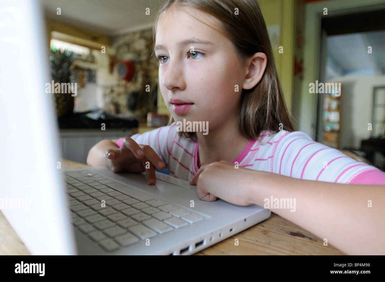 Un 9 anno vecchia ragazza al computer in cucina Foto Stock